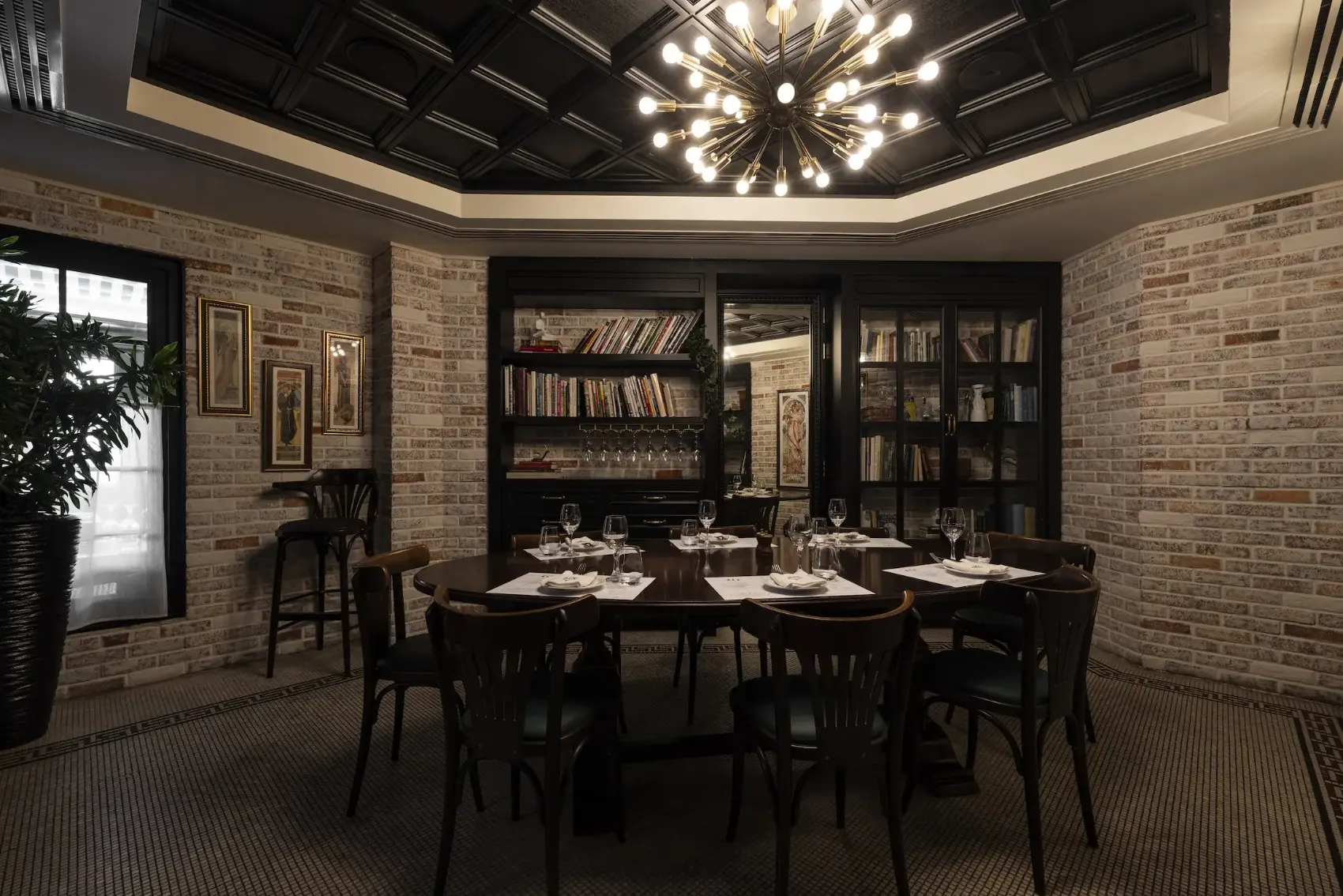 A private dining room with a round table, bookshelves and framed artwork